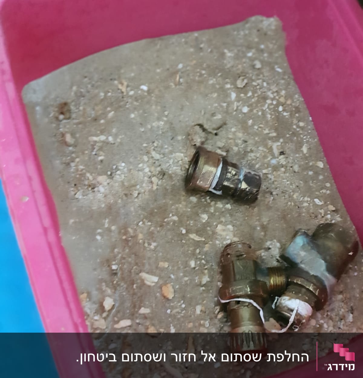 חלקי מתכת בתוך מיכל ורוד עם חול